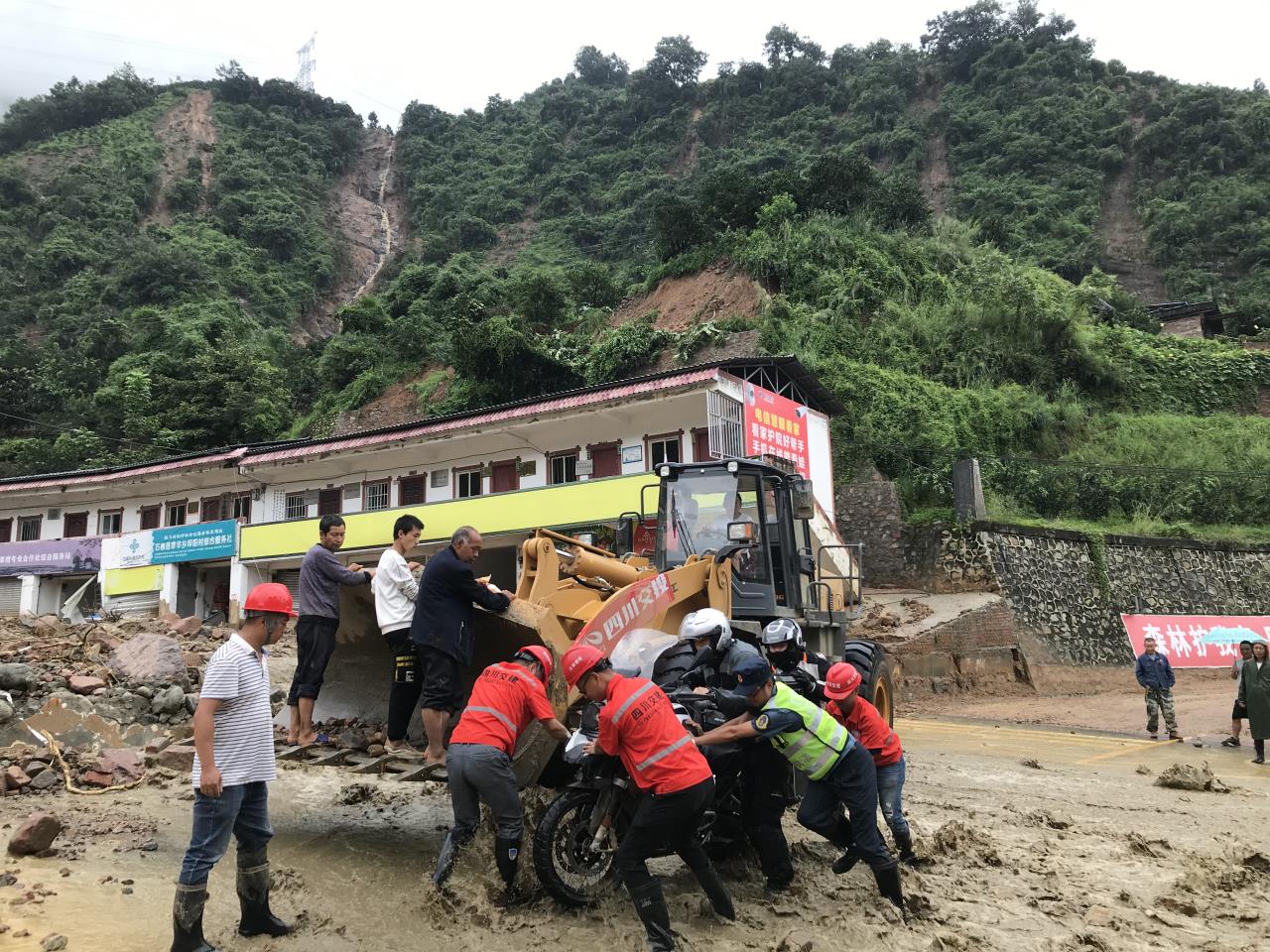 8月18日，抢险人员与民警帮助被困群众的摩托车通过涉水路面.jpg